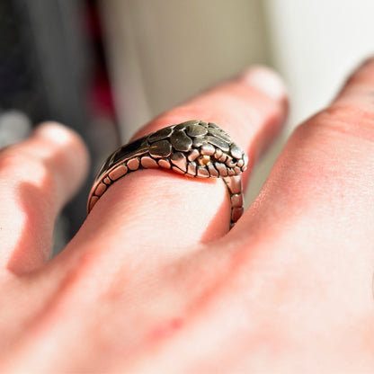 Vintage sterling silver snake ring with 18K gold accents and iridescent abalone shell inlay, coiled around a finger.