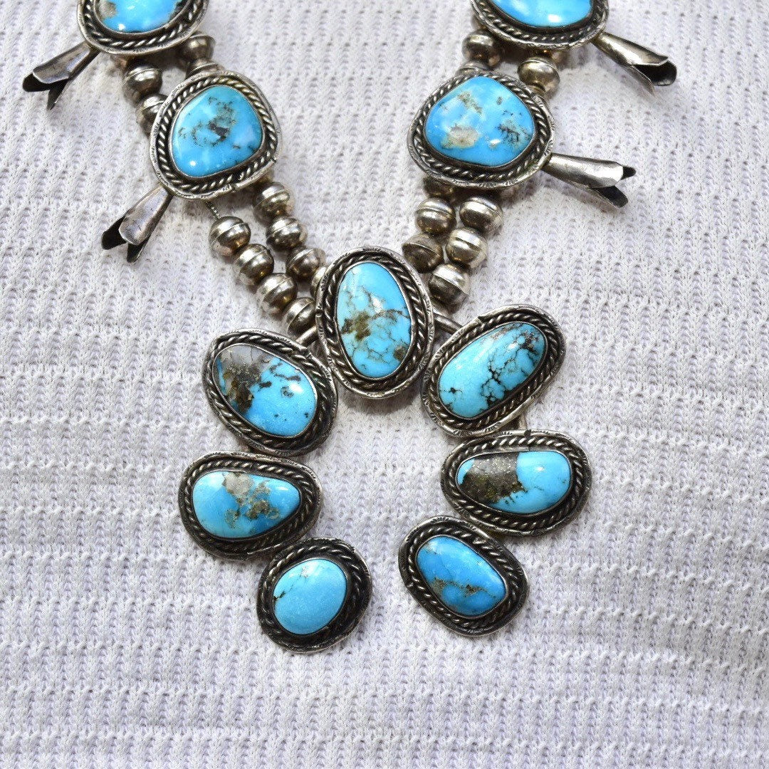 Vintage Navajo squash blossom necklace featuring natural blue turquoise stones set in coin silver, an example of traditional Native American old pawn jewelry. The necklace measures 29 inches long and showcases the iconic squash blossom design with multiple oval turquoise cabochons accented by silver petals.