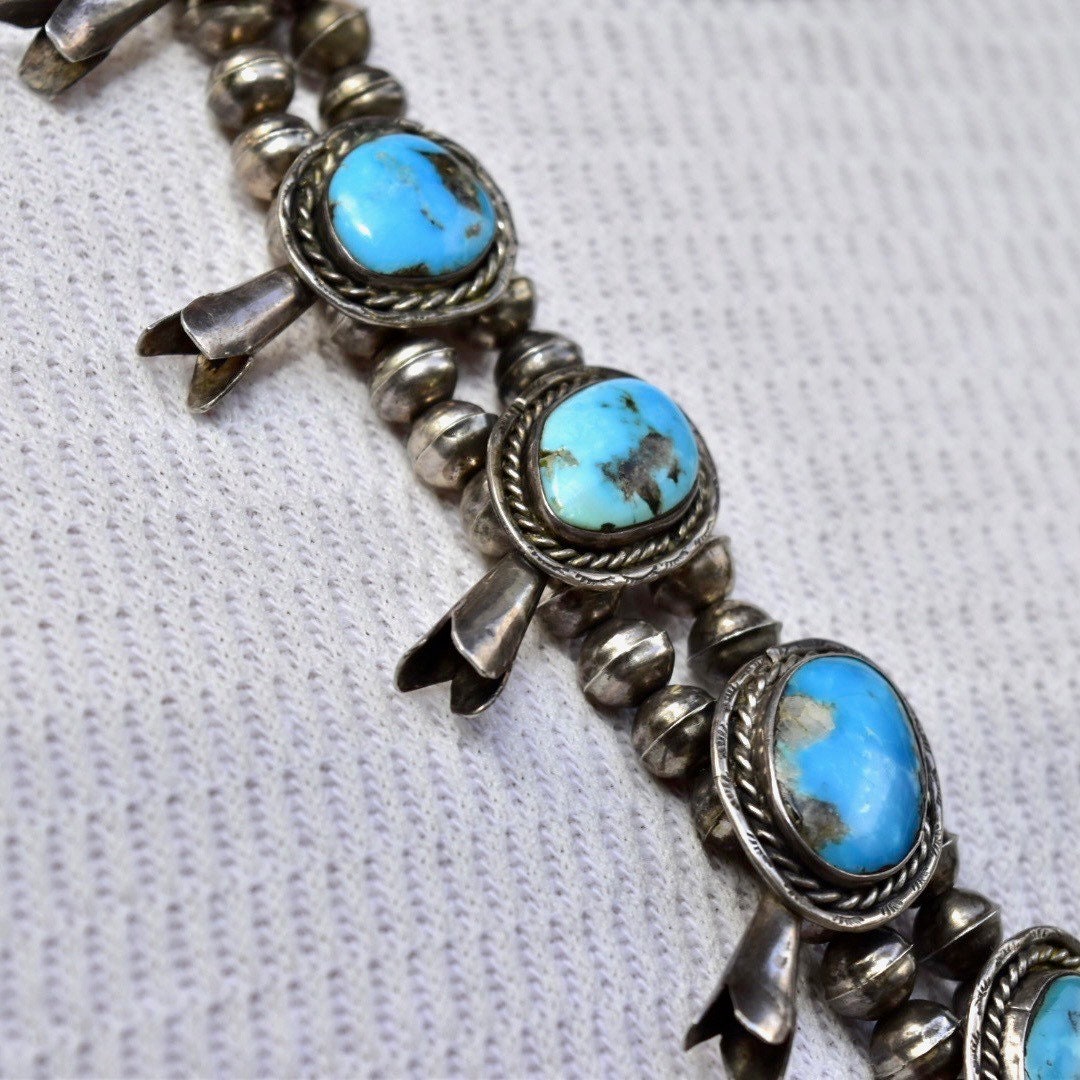 Vintage Navajo squash blossom necklace featuring natural blue turquoise stones set in coin silver, crafted as traditional Native American old pawn jewelry. The necklace measures 29 inches in length and showcases the iconic squash blossom design with ornate silver beads and vibrant turquoise cabochons.