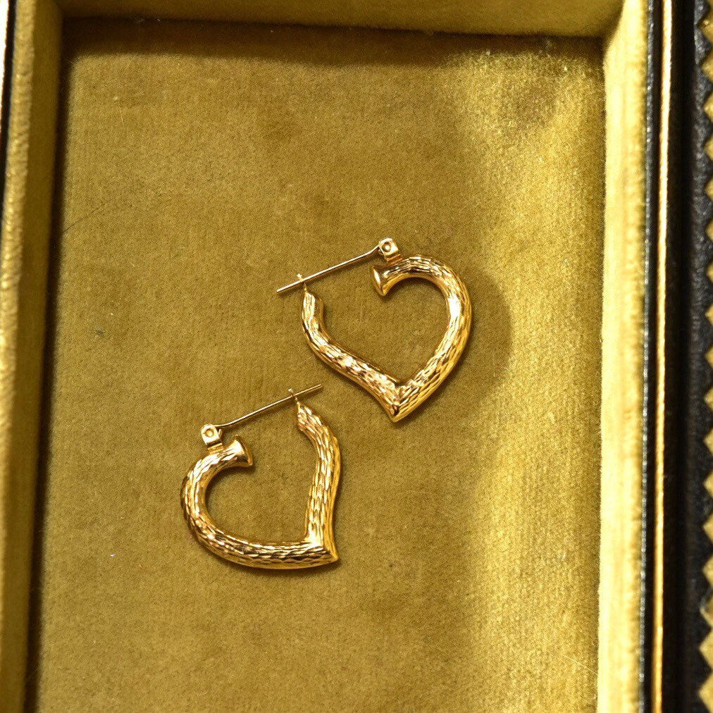 Vintage 14K yellow gold hammered heart hoop earrings in textured finish, displayed in a gold jewelry box.