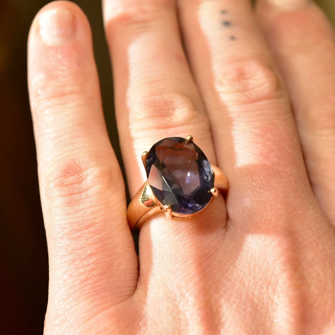 Vintage gold plated sterling silver ring with large oval-cut simulated blue gemstone on hand, showcasing the cocktail ring's vibrant color and elegant design in a size 7 US.