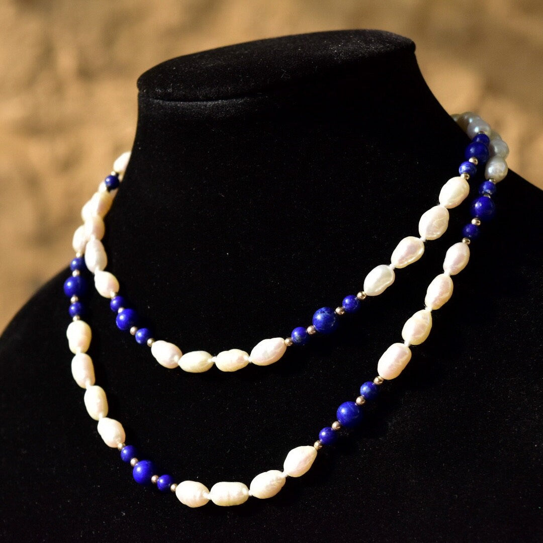 Vintage 14K gold necklace featuring knotted fresh water baroque pearls and polished lapis lazuli beads, accented with gold beads, measuring 29 inches in length, displayed on a black velvet bust.