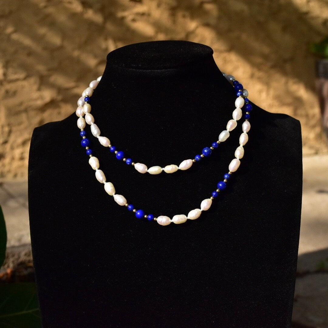 Vintage 14K gold necklace with knotted freshwater pearls and polished lapis lazuli beads, accented by gold beads, displayed on a black jewelry bust against a textured background.