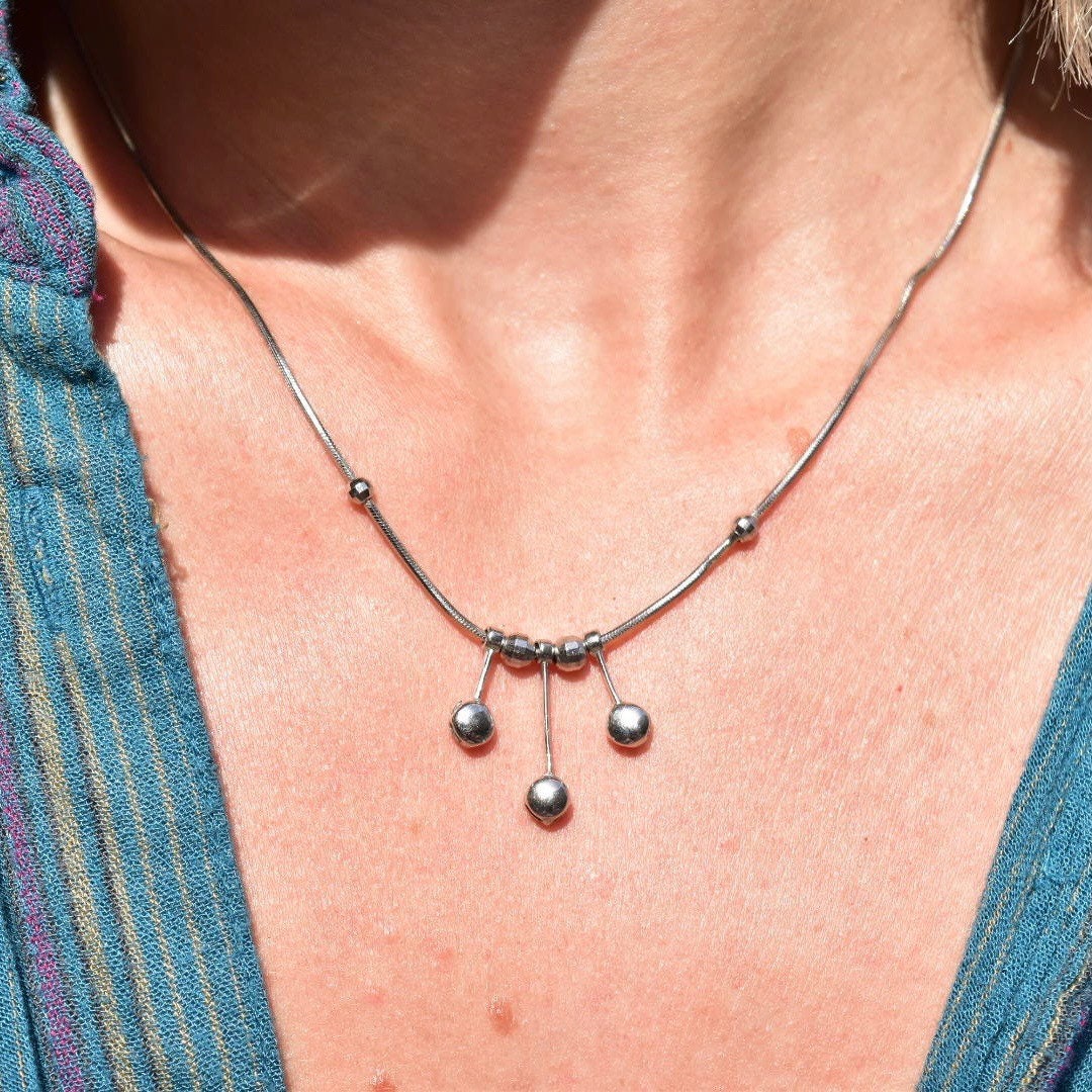 Vintage Italian 14K white gold modernist tassel necklace with multi-bead pendant hanging from a thin gold snake chain on a woman's neck and chest.