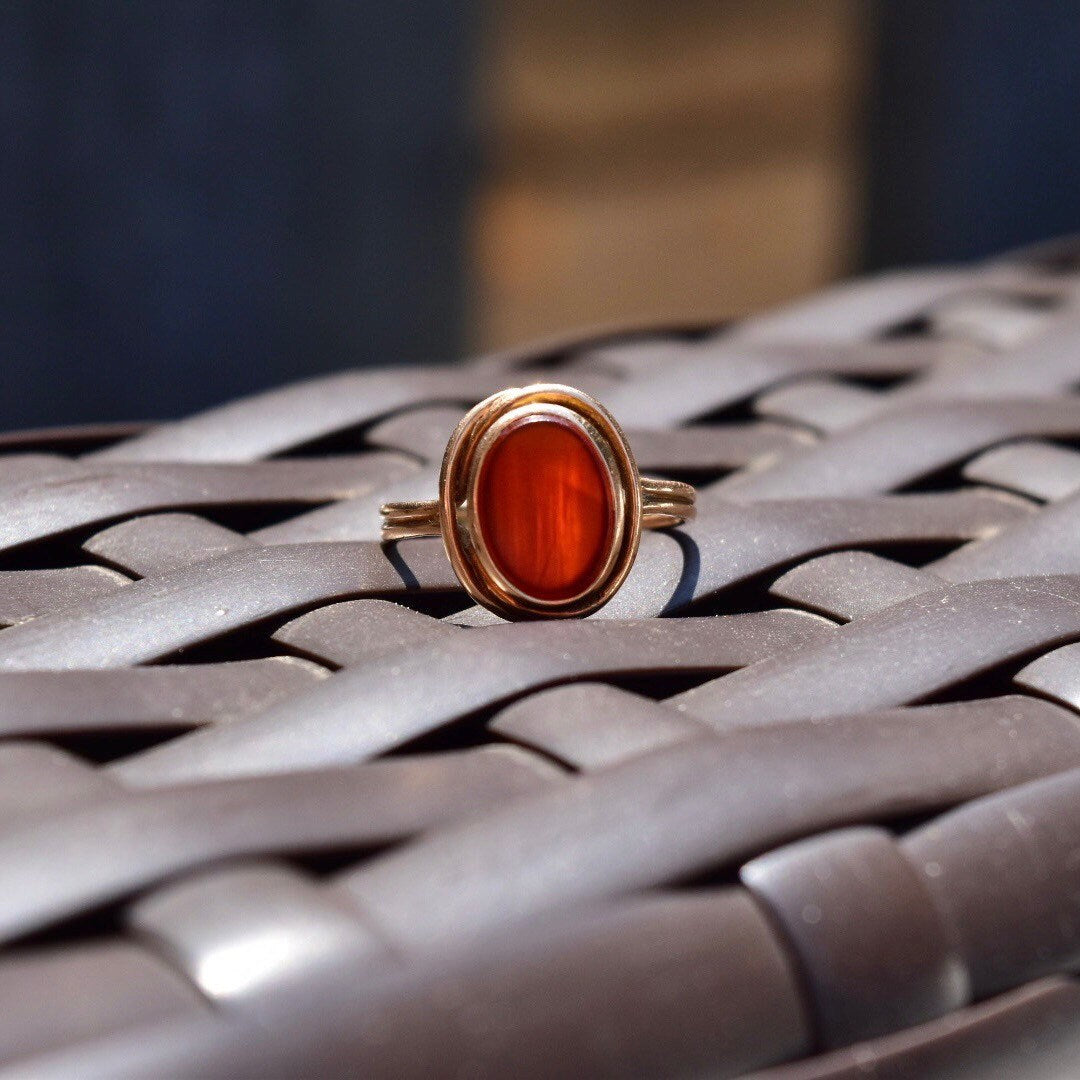 Vintage 14K gold modernist ring with translucent red carnelian gemstone, size 7 US, on woven metal background