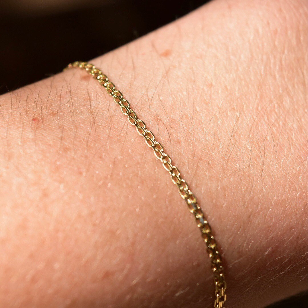 14K gold flat mesh Bismark chain bracelet with spring-ring clasp on a person's wrist, minimalist jewelry, 2mm wide links, 7 inches long.