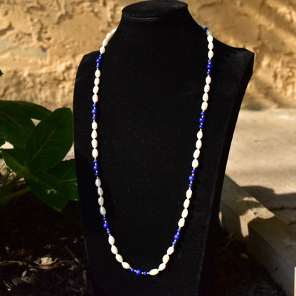 Vintage 14K fresh water pearl and lapis lazuli knotted bead necklace displayed on black jewelry stand against stone background.