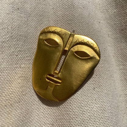 Vintage gold-toned abstract modernist tribal face mask brooch pin by Maxine Denker, engraved face mask design, unique lapel or jacket accessory, measuring 45 mm in size.