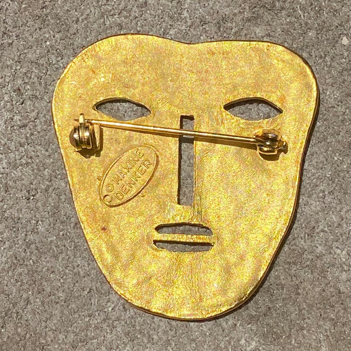 Vintage gold-toned abstract tribal face mask brooch pin with engraved details, modernist style unique jacket accessory, measuring 45 mm.