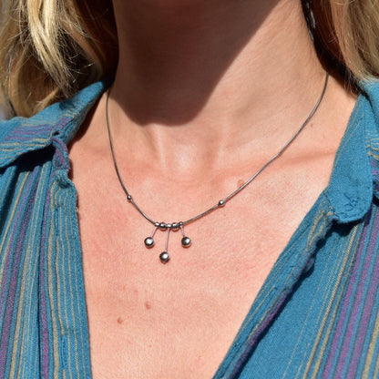 Close-up image of a woman's neck and upper chest wearing a delicate vintage Italian 14K white gold necklace featuring a pendant with multiple small gold beads forming a tassel design, suspended from a thin 1mm gold snake chain. The necklace is approximately 17 inches in length.