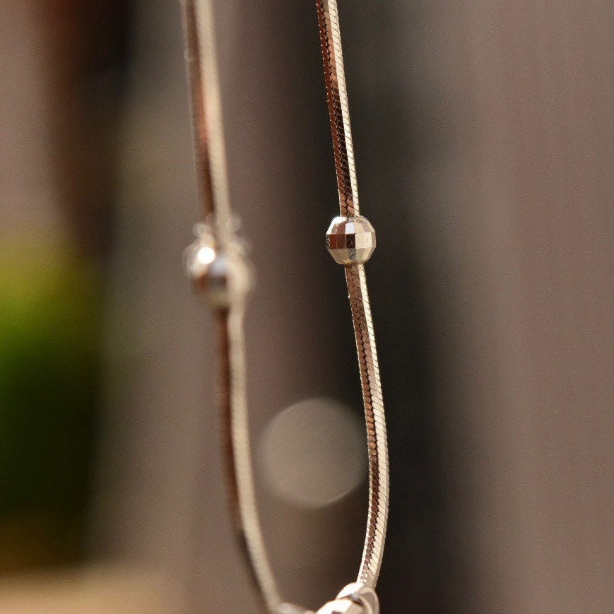 Vintage 14K white gold tassel necklace with multi-bead pendant on delicate snake chain against blurred background, showcasing intricate modernist Italian design.