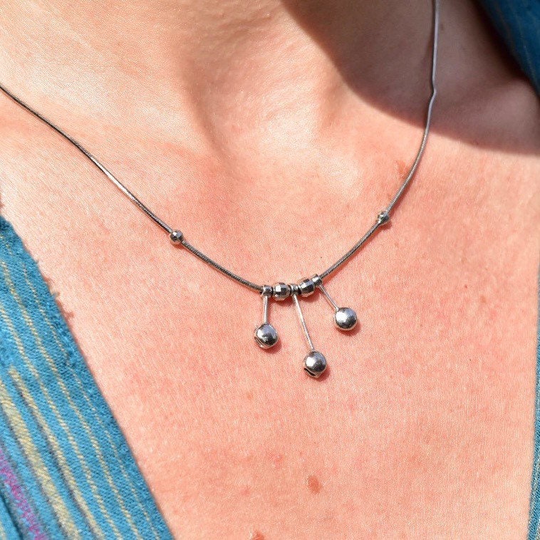 Vintage Italian 14K white gold tassel necklace with multi-bead pendant on a thin gold snake chain, shown worn around a woman's neck and upper chest.