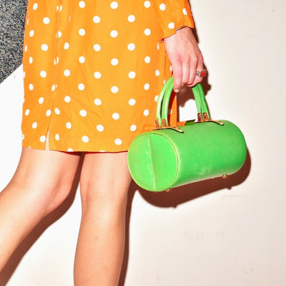 Mod polka dot dress with green barrel-shaped handbag