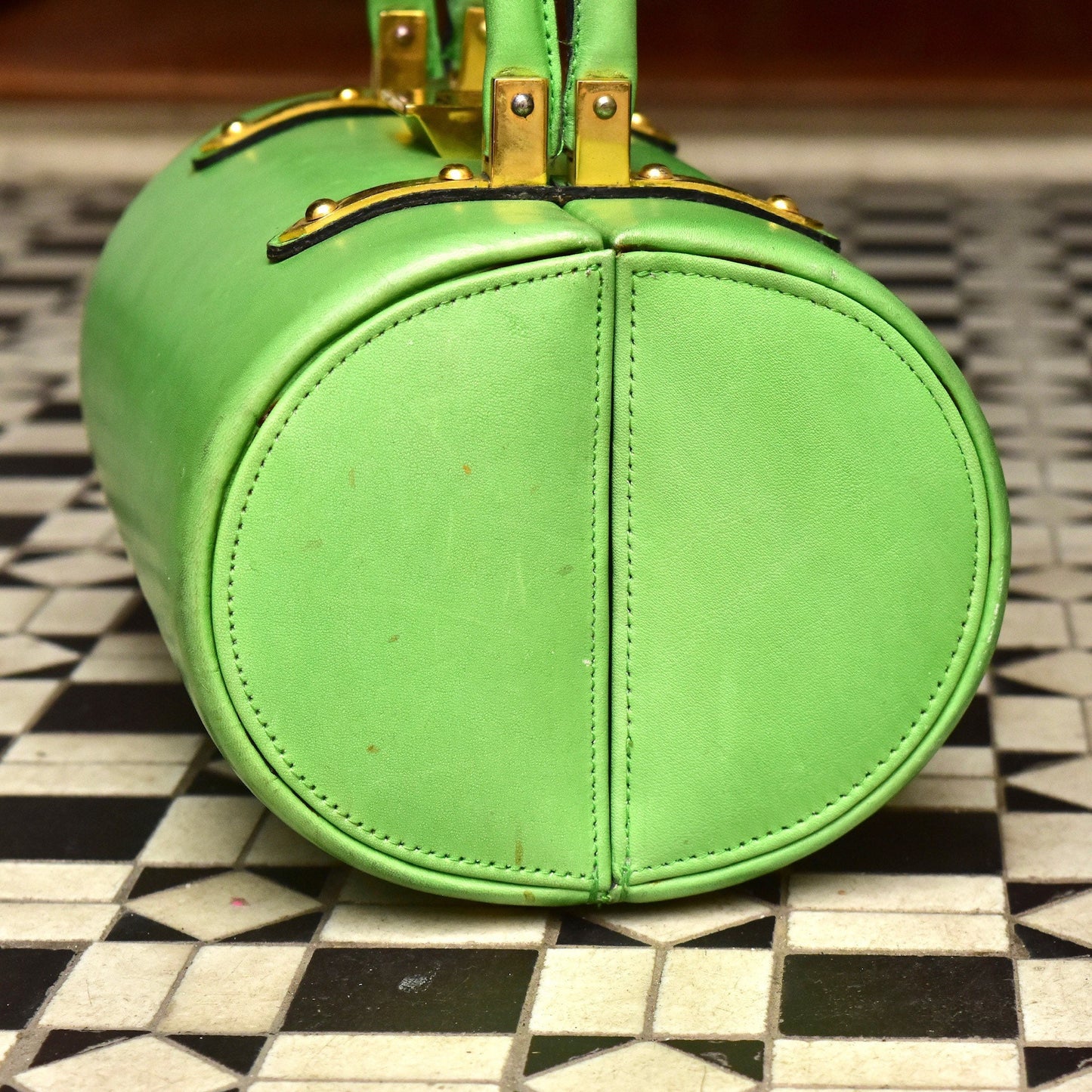 Mod TANO of Madrid lime green leather barrel box purse with brass hardware on checkered floor, retro hard shell top handle box bag, 8 1/2" wide