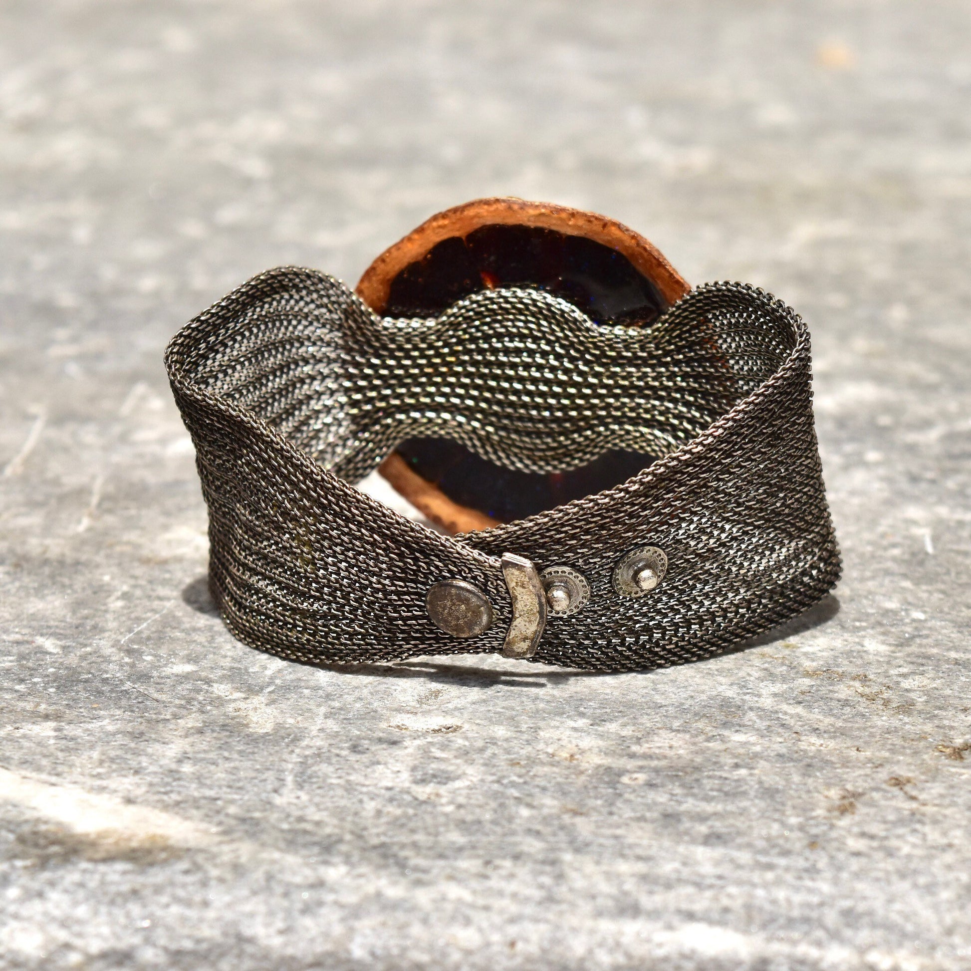 Unique silver mesh cuff bracelet with preserved orange slice accent in iridescent purple glaze, adjustable from 6 1/2 to 7 1/4 inches long.