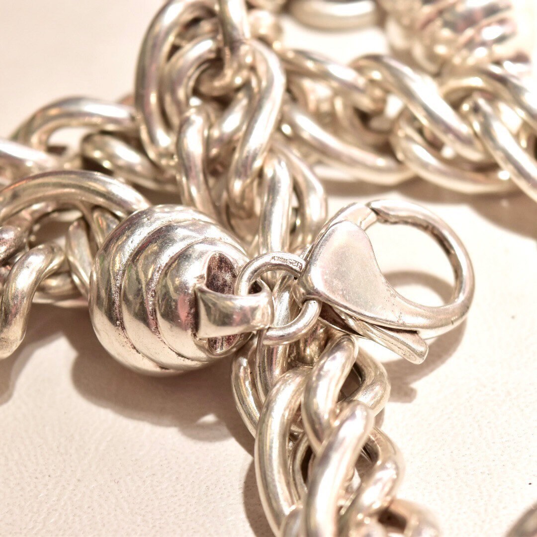 Silver chain link necklace with chunky twisted and coiled links on white background