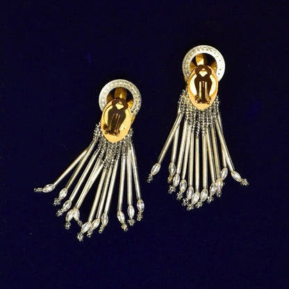 Vintage gold-tone chandelier clip-on earrings with intricate beaded design and teardrop tassels, measuring 3 3/4 inches long, displayed on dark blue background.