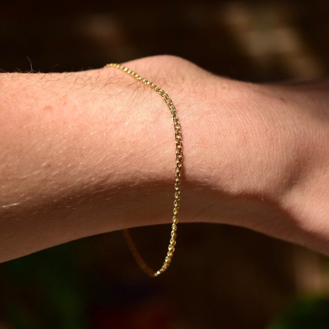 14K gold Bismark chain bracelet on wrist, featuring flat 2mm mesh links and spring-ring clasp closure, minimalist jewelry style, 7 inches long.