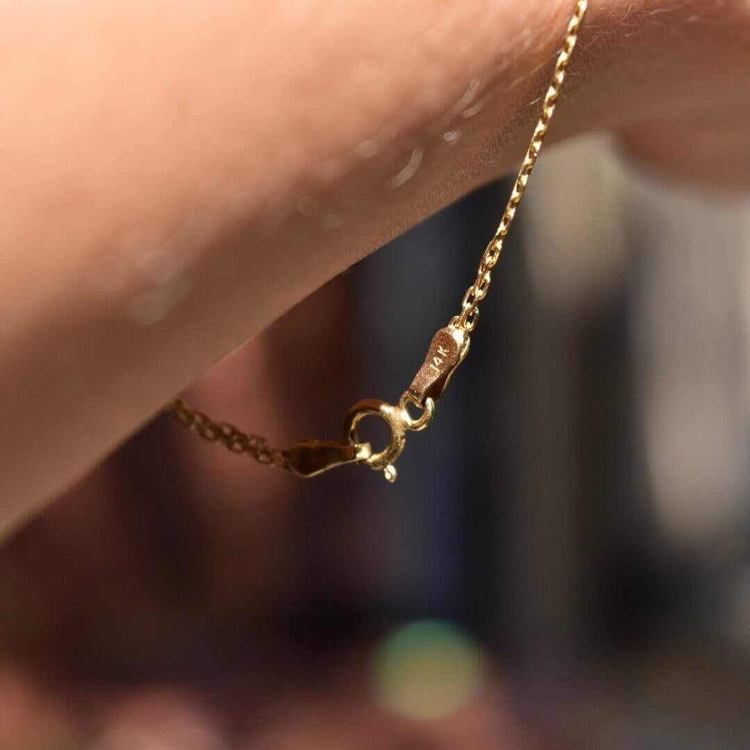 14K gold Bismark chain bracelet with 2mm flat mesh links and spring-ring clasp on a blurred background, showcasing minimalist jewelry design.