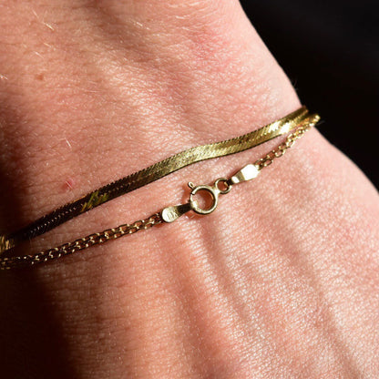 14K gold bismark chain bracelet on wrist, featuring 2mm flat mesh links and a spring-ring clasp closure, creating a minimalist jewelry piece measuring 7 inches long.