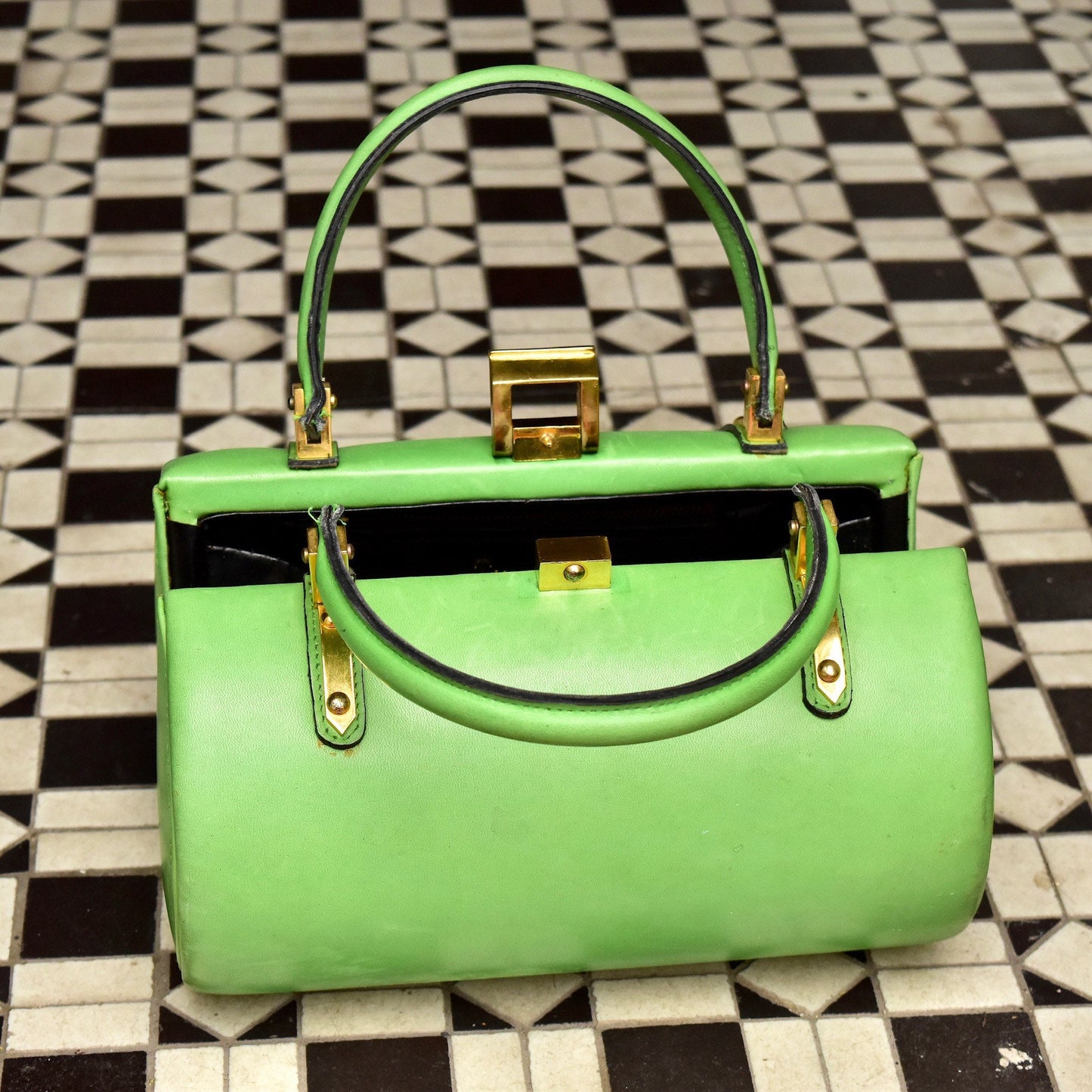 Lime green leather barrel box purse with brass hardware on checkered floor