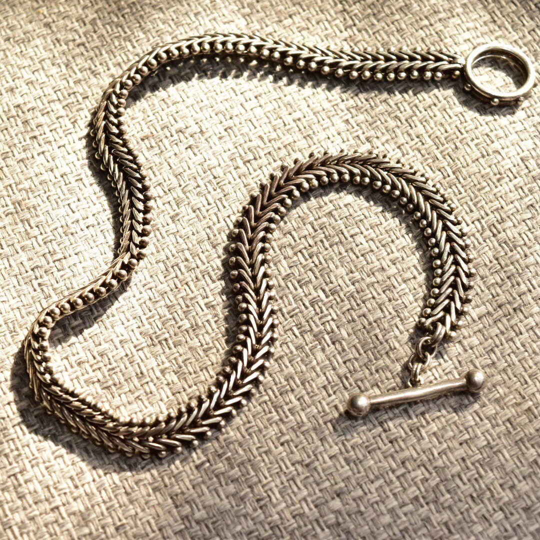 Sterling silver foxtail chain necklace with toggle clasp on textured fabric background, 17 inches long