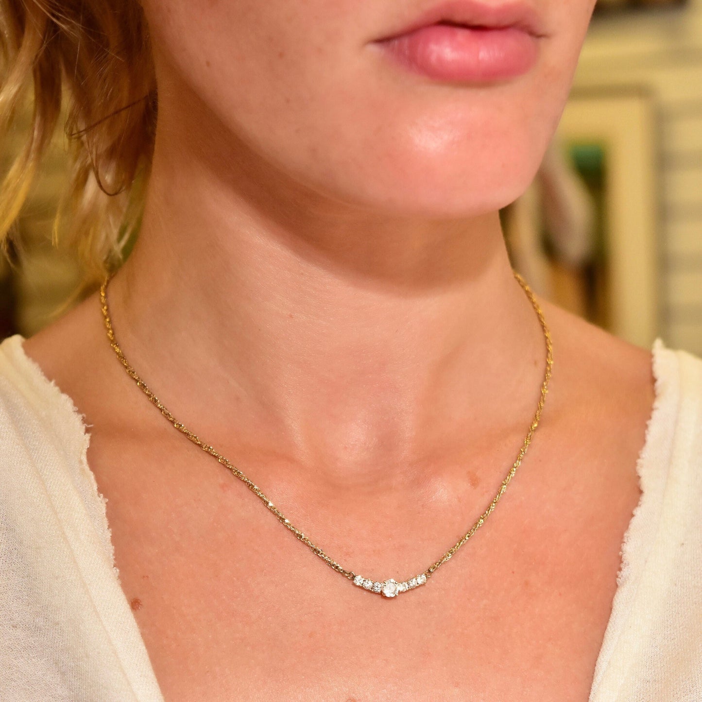 14K yellow gold diamond bar necklace with shared prong setting on a model's neck, featuring an elegant 2mm Singapore chain collar that is 17 1/2 inches long.