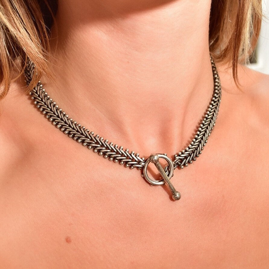 Sterling silver foxtail toggle chain necklace worn around a woman's neck, showing the intricate braided design and toggle clasp closure against her skin.