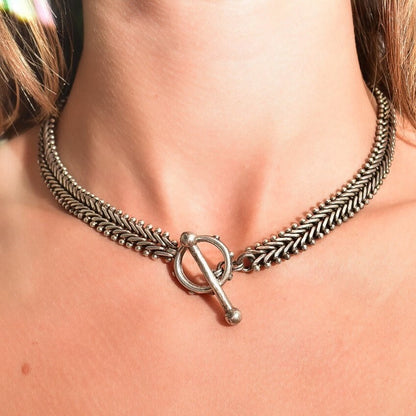 Sterling silver foxtail chain necklace with toggle clasp worn around a person's neck, showing the intricately woven chain links and silver toggle closure against bare skin.