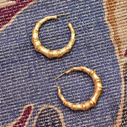 14K yellow gold bamboo hoop earrings, 35mm vintage statement stud hoops, on textured multicolor fabric background