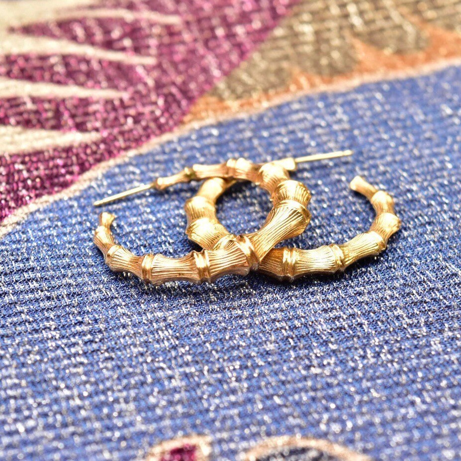 14K yellow gold bamboo hoop earrings, vintage statement stud hoops, 35mm diameter, on colorful patterned fabric background