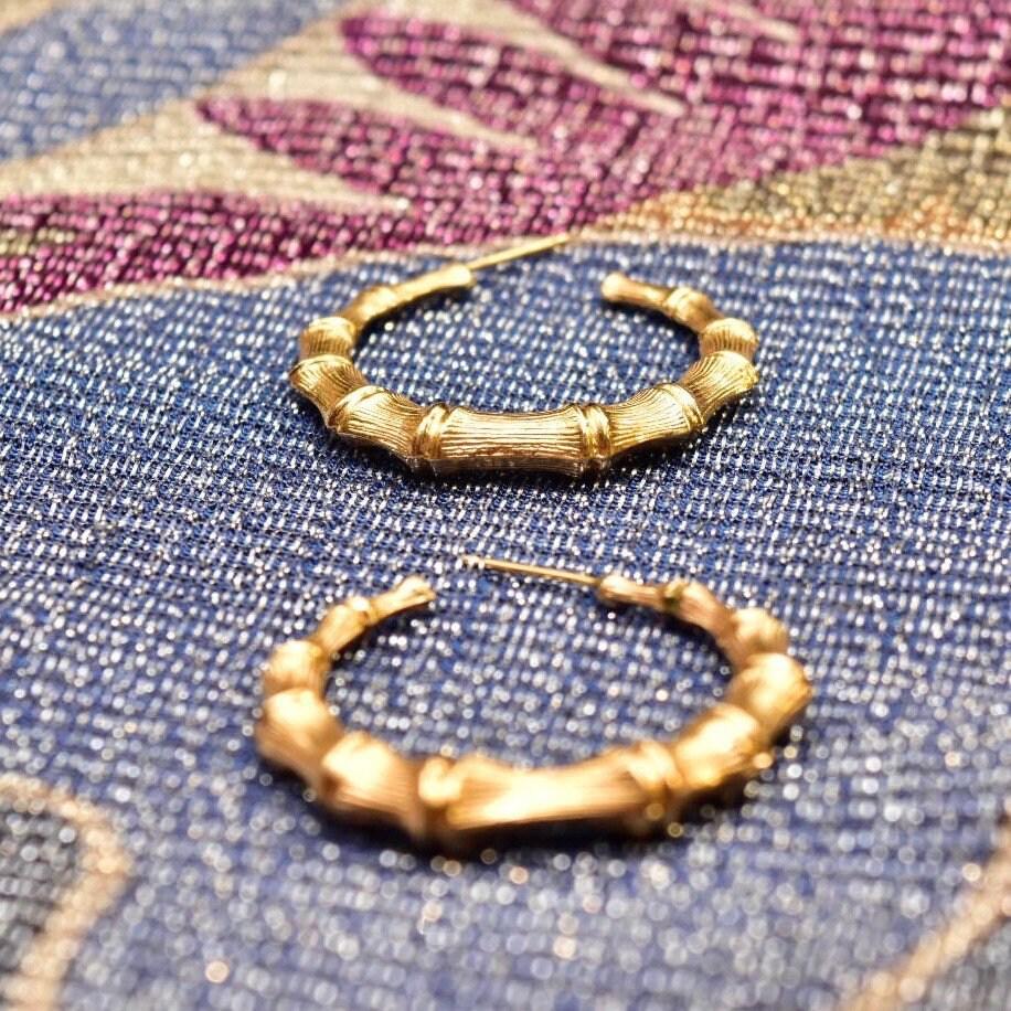 14K yellow gold bamboo hoop earrings on colorful patterned fabric background, vintage statement jewelry with lustrous shine, 35mm size.