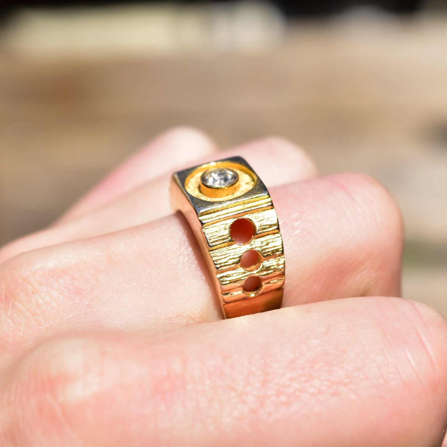 18K gold-plated modernist signet ring with diamond, textured design and circle cutouts, shown on a hand, size 9 US.