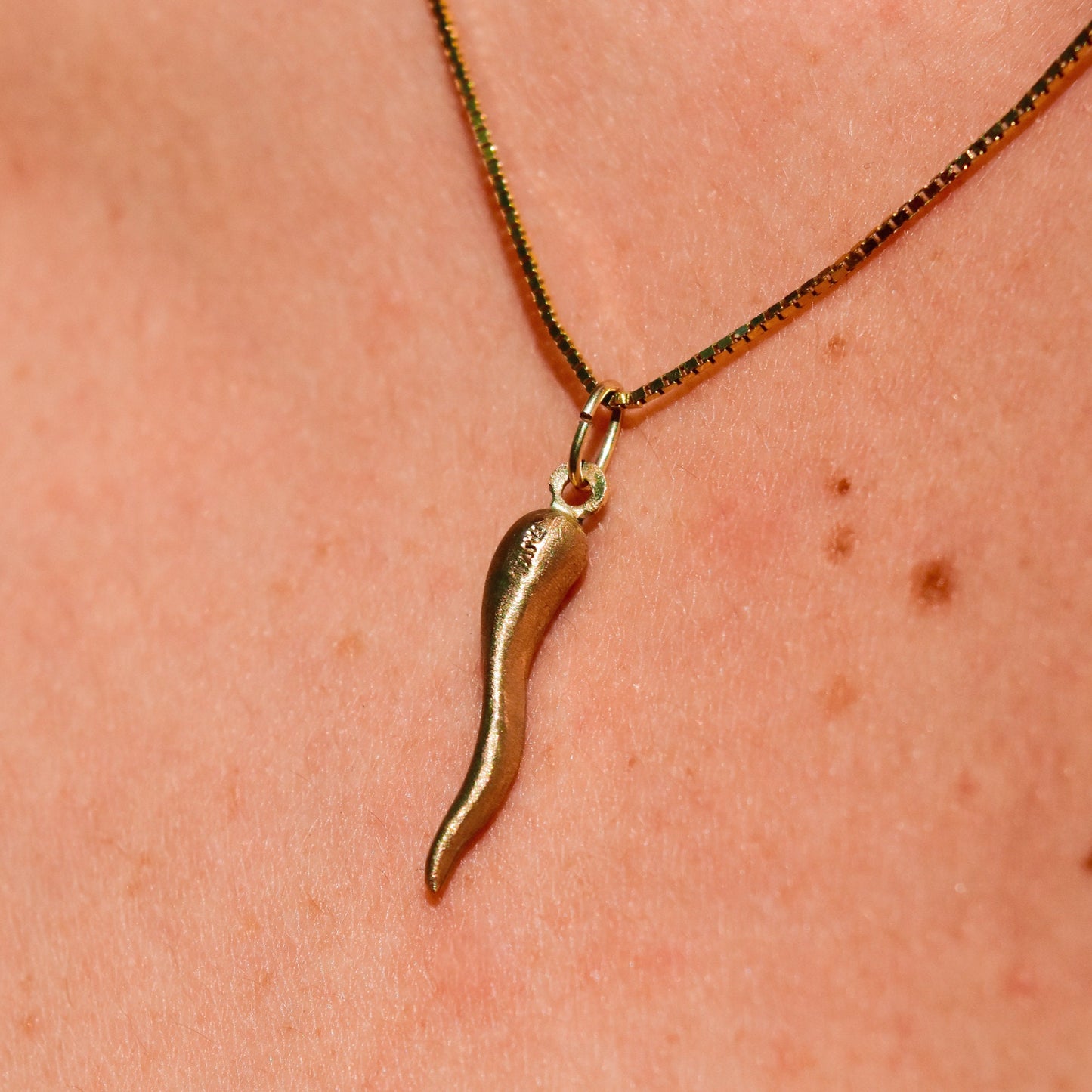 14K yellow gold Italian horn pendant necklace on skin, small brushed gold cornicello charm for good luck