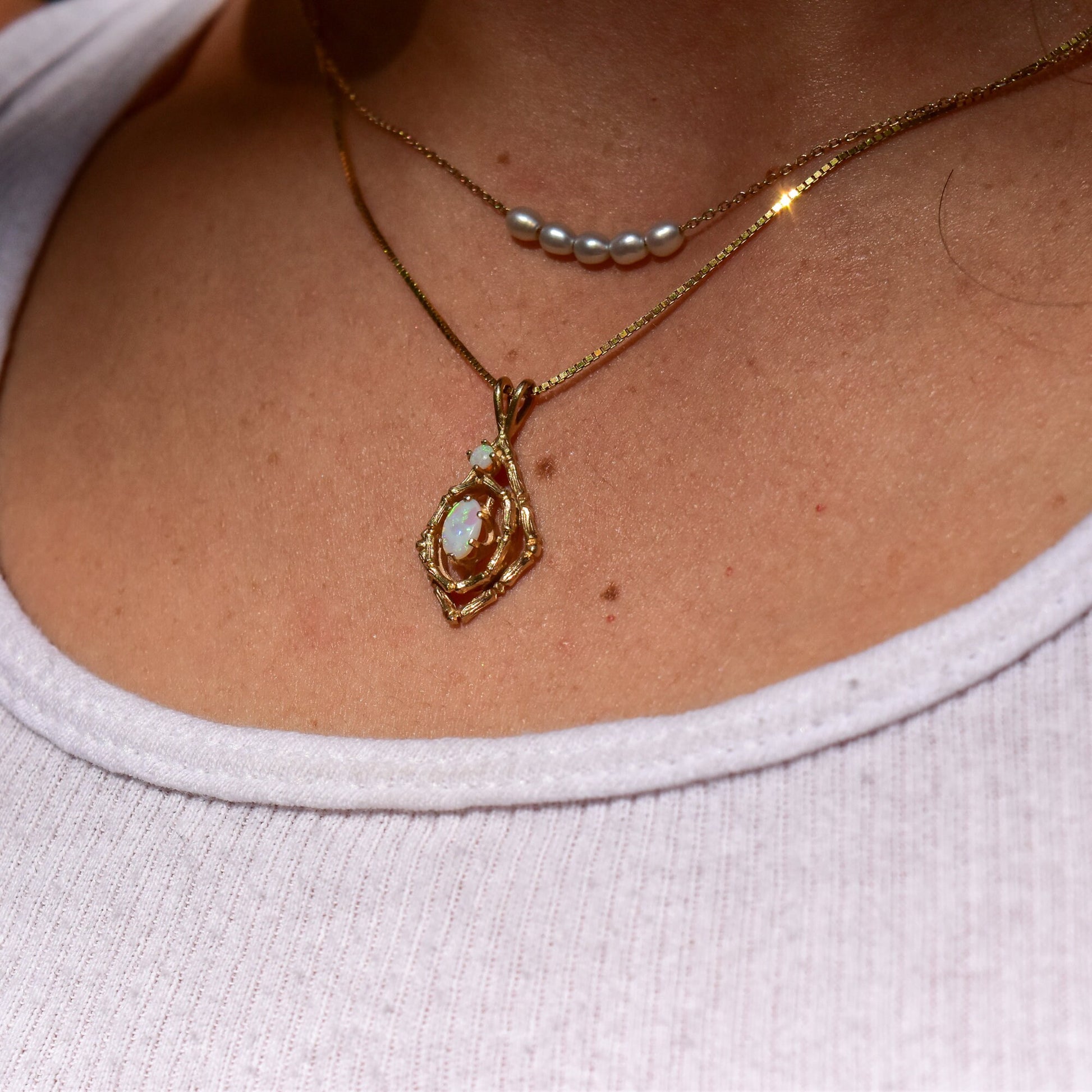 10K yellow gold bamboo motif pendant necklace with two white opal cabochon stones, estate jewelry piece showcased on woman's neck and upper chest.