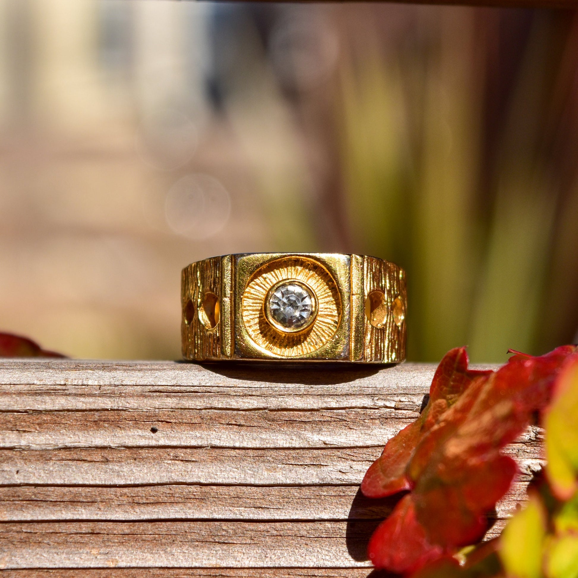 18K gold-plated textured signet ring with circular diamond accent on weathered wooden surface with autumn leaves