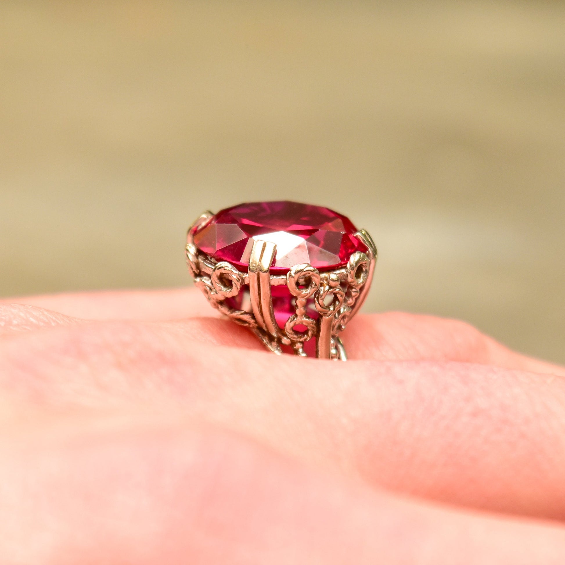 10K white gold pink synthetic ruby cocktail ring with ornate filigree setting, Art Deco style, size 6 3/4 US, displayed on an open hand