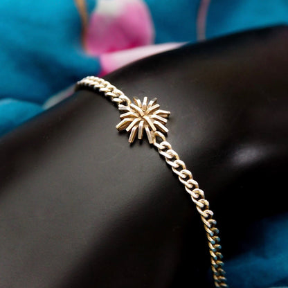 Vintage sterling silver curb link bracelet with starburst flower accent on black surface, with blue fabric visible in blurred background.