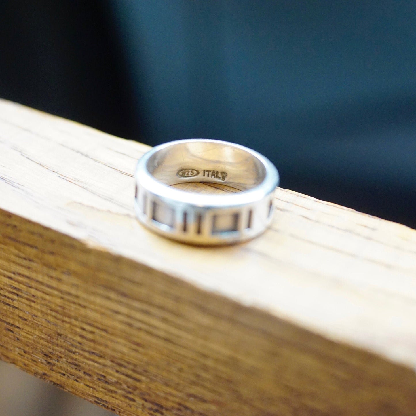 Vintage Tiffany & Co. 1995 sterling silver Atlas ring with embossed roman numeral design, made in Italy, petite silver band, size 6 US, shown on wooden surface.