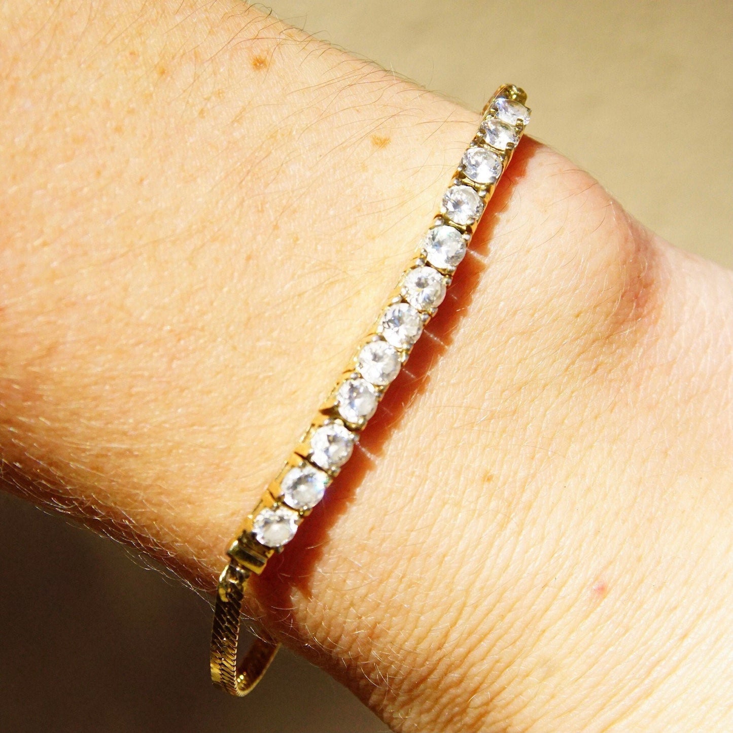 Vintage gold plated sterling silver cubic zirconia diamond bar bracelet on wrist, featuring 2.5mm herringbone chain and 12 brilliant CZ diamonds, measuring 7 1/8 inches long.