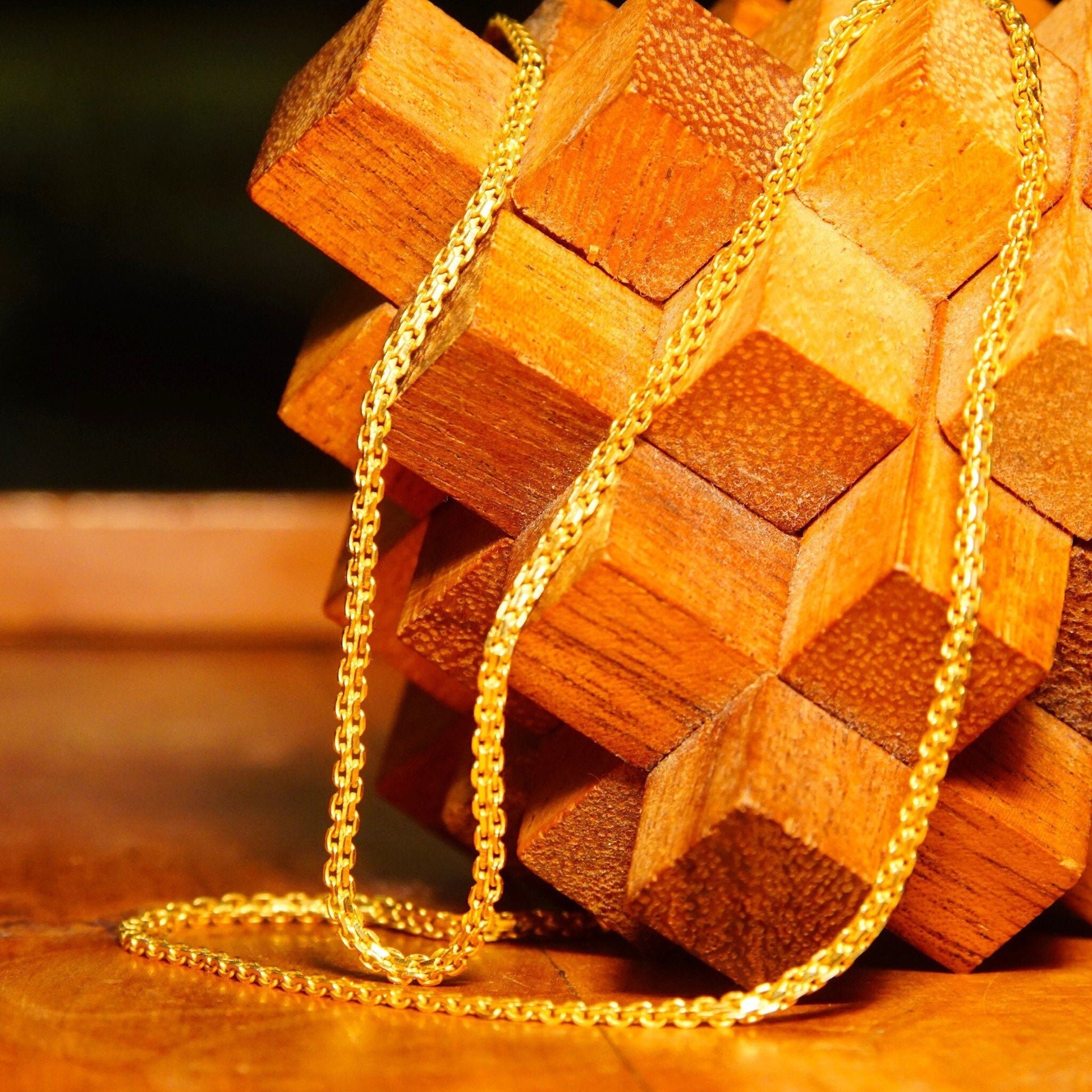 Vintage KDM 22KT yellow gold Bombay Bismark chain necklace draped over wooden blocks, showing the intricate woven flat fence chain design of the minimalist gold choker, made in India.