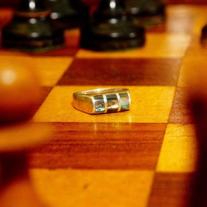 Vintage sterling silver ring with abalone inlay on wooden chessboard