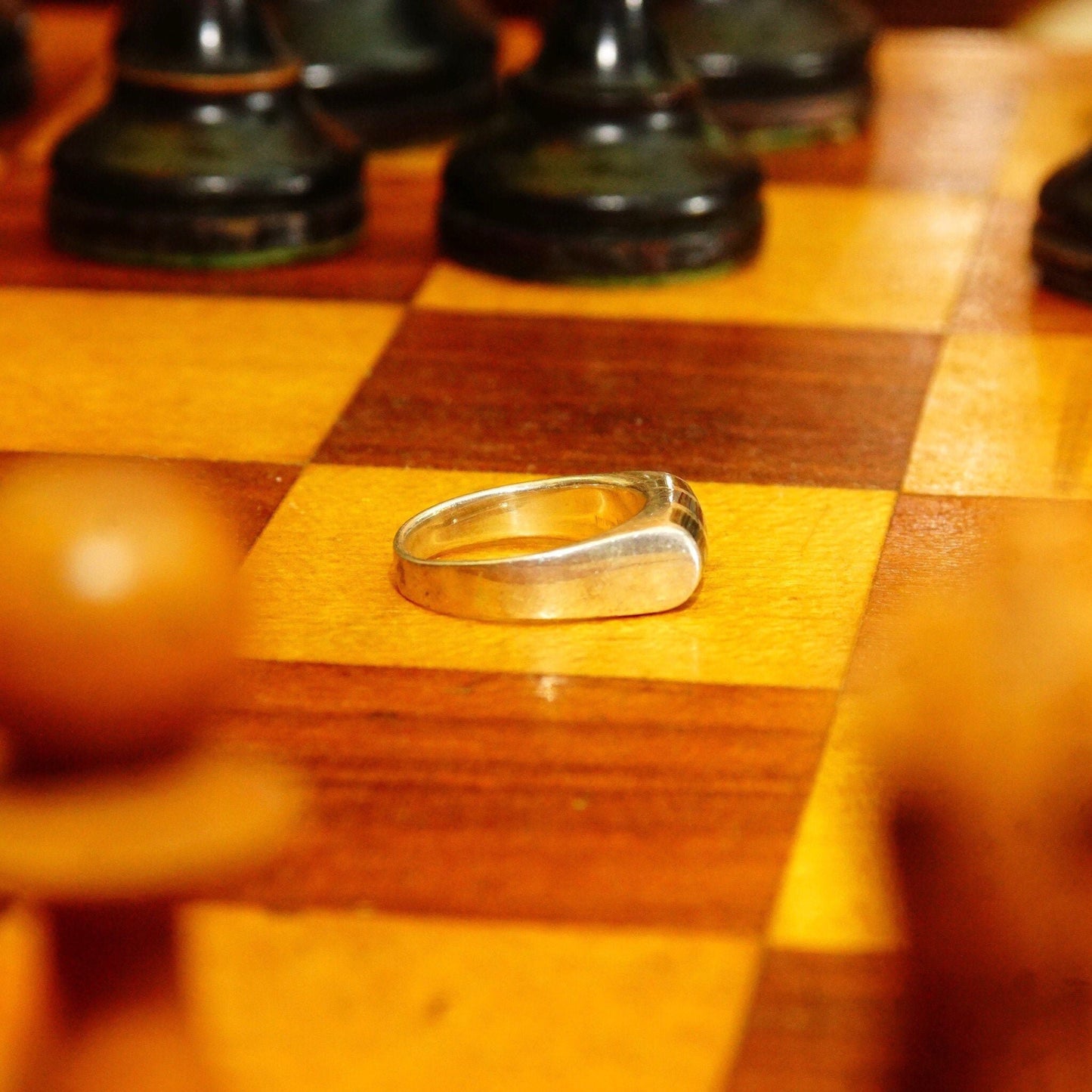 Vintage sterling silver ring on wooden chessboard with chess pieces in background