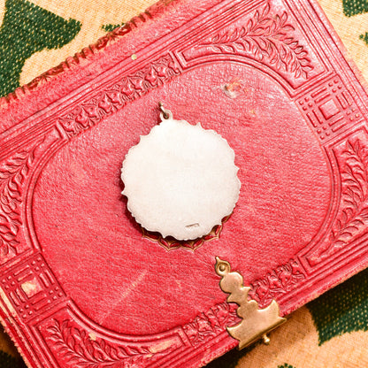 Vintage style sterling silver pendant featuring a hand-carved bovine bone flower with etched details set on an ornate textured red background.