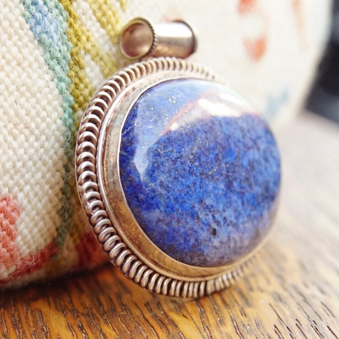 Vintage modernist lapis lazuli and sterling silver pendant featuring a large, marbled blue lapis stone set in an ornate silver bezel, measuring approximately 2 1/2 inches long by 2 3/4 inches wide.