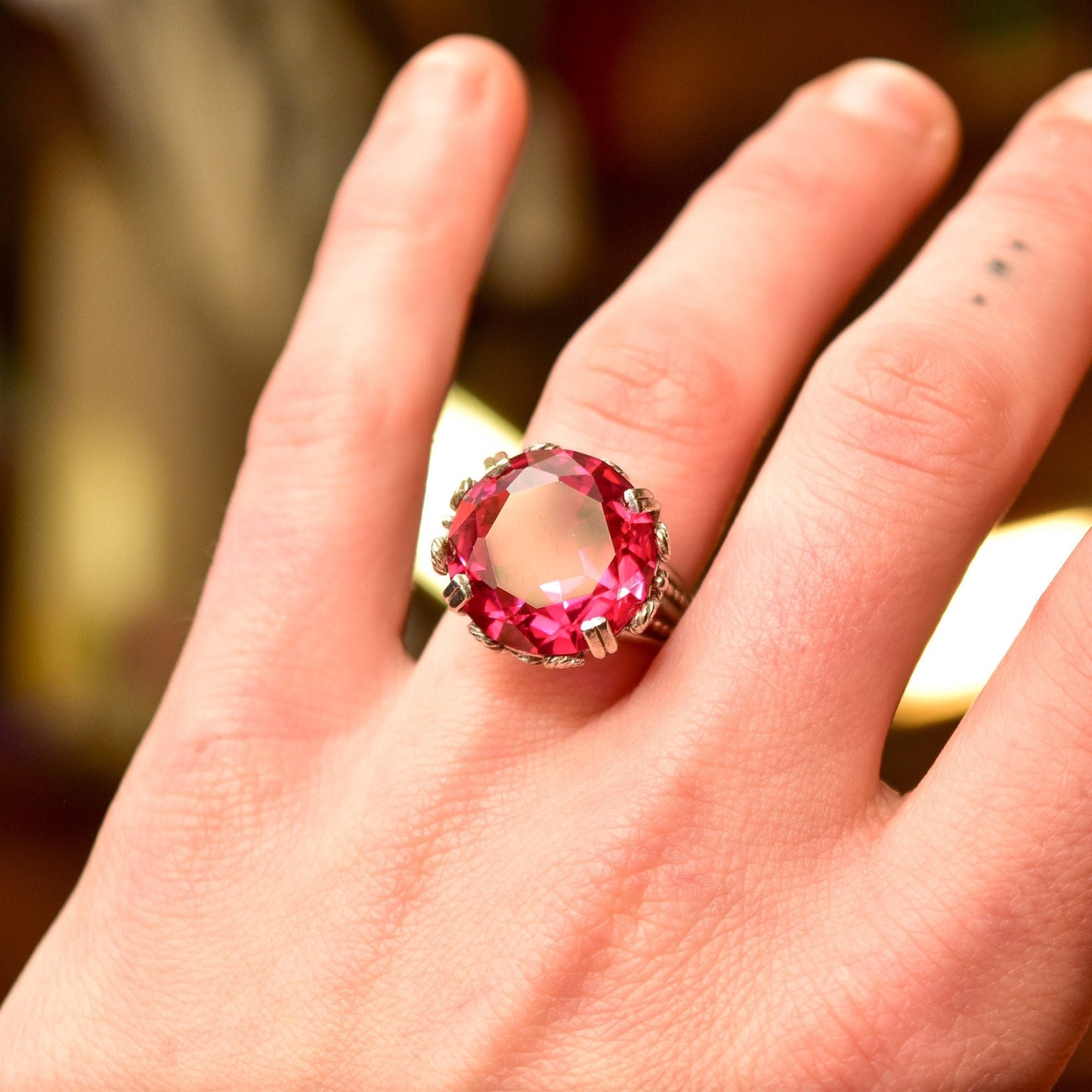 10K white gold pink ruby cocktail ring with ornate filigree setting on a hand, featuring a large round synthetic ruby gemstone, in Art Deco style, size 6 3/4 US.