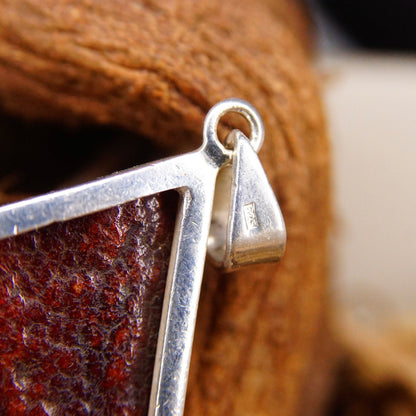 Vintage modernist sterling silver pendant necklace featuring a honey amber stone with incredible fossilized tree resin inclusions, set in an abstract 925 silver setting.