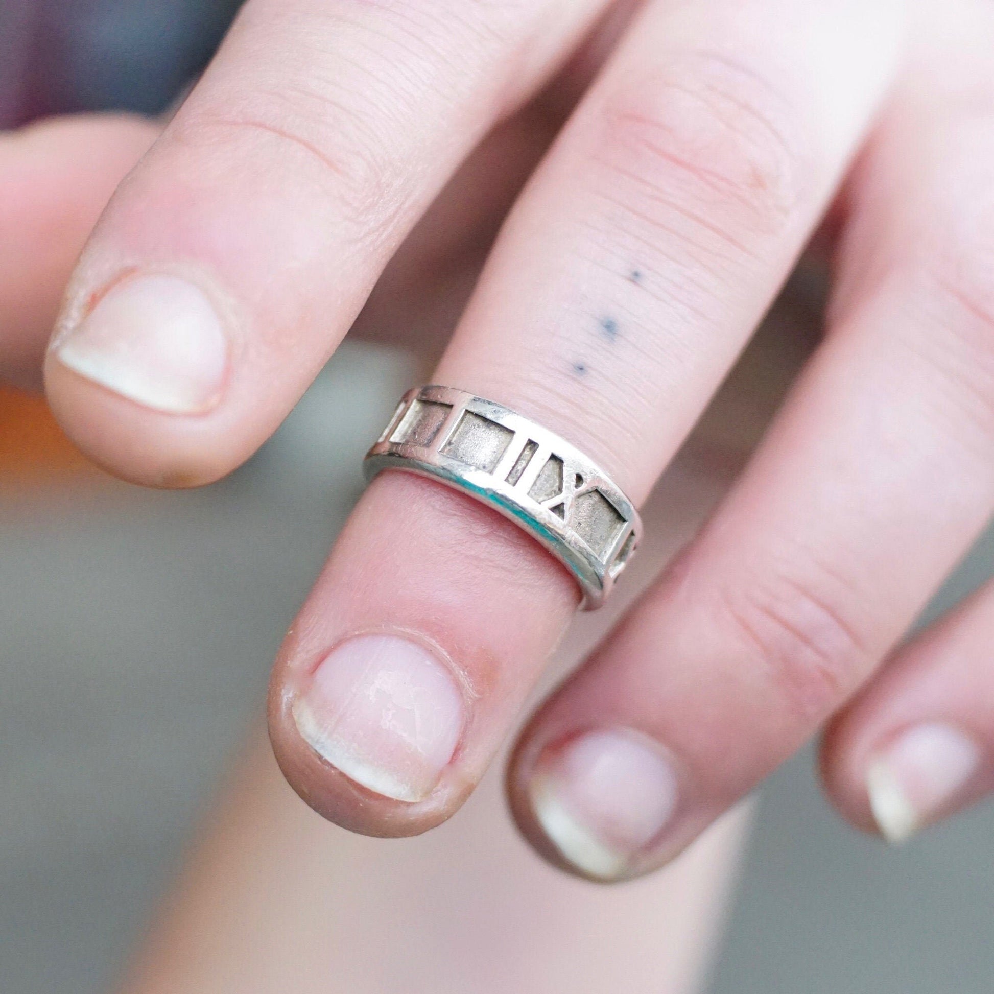 Vintage Tiffany & Co. sterling silver Atlas ring with embossed Roman numeral design on a hand, size 6 US.