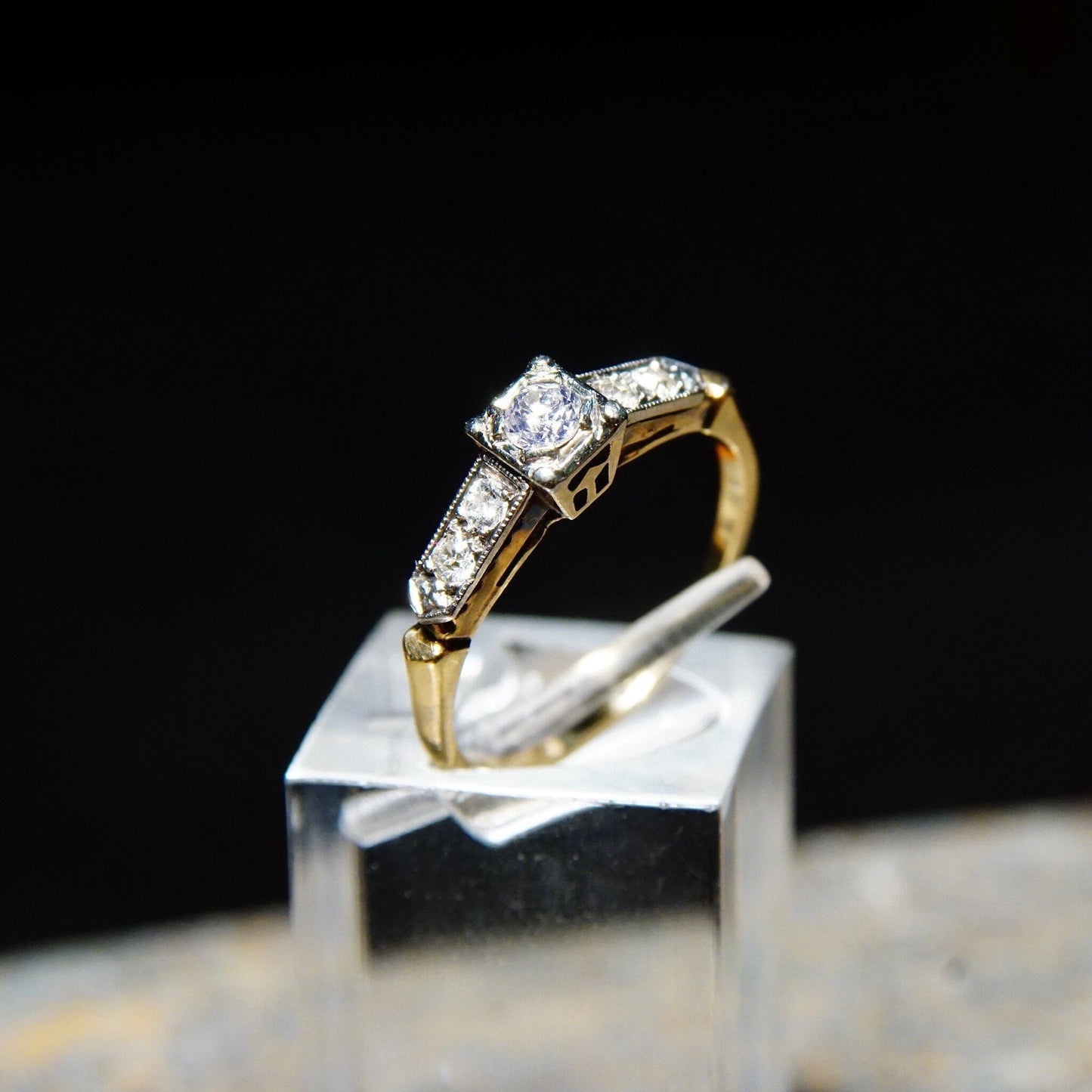 Vintage 14K yellow gold and 18K white gold diamond engagement ring with .14 carat old European cut center stone on display stand, ring size 6 1/4 US.