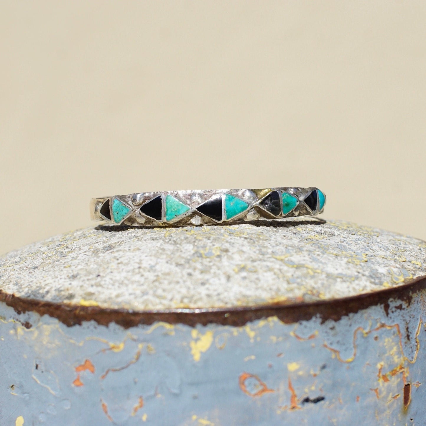 Vintage Zuni inlaid turquoise and onyx silver cuff bracelet featuring a geometric triangle pattern, measuring 4 3/4 inches long, petite size Native American jewelry from the 1970s era.